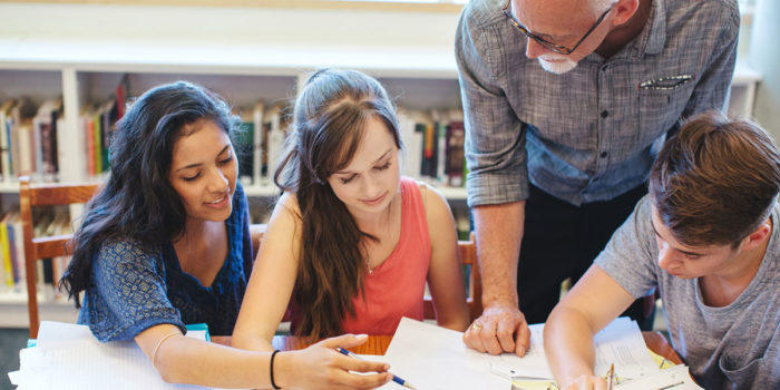 Teacher helping highschool students learn in library